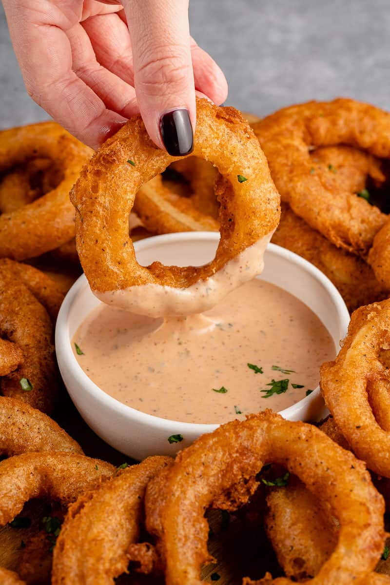 dipping beer battered onion rings into sauce