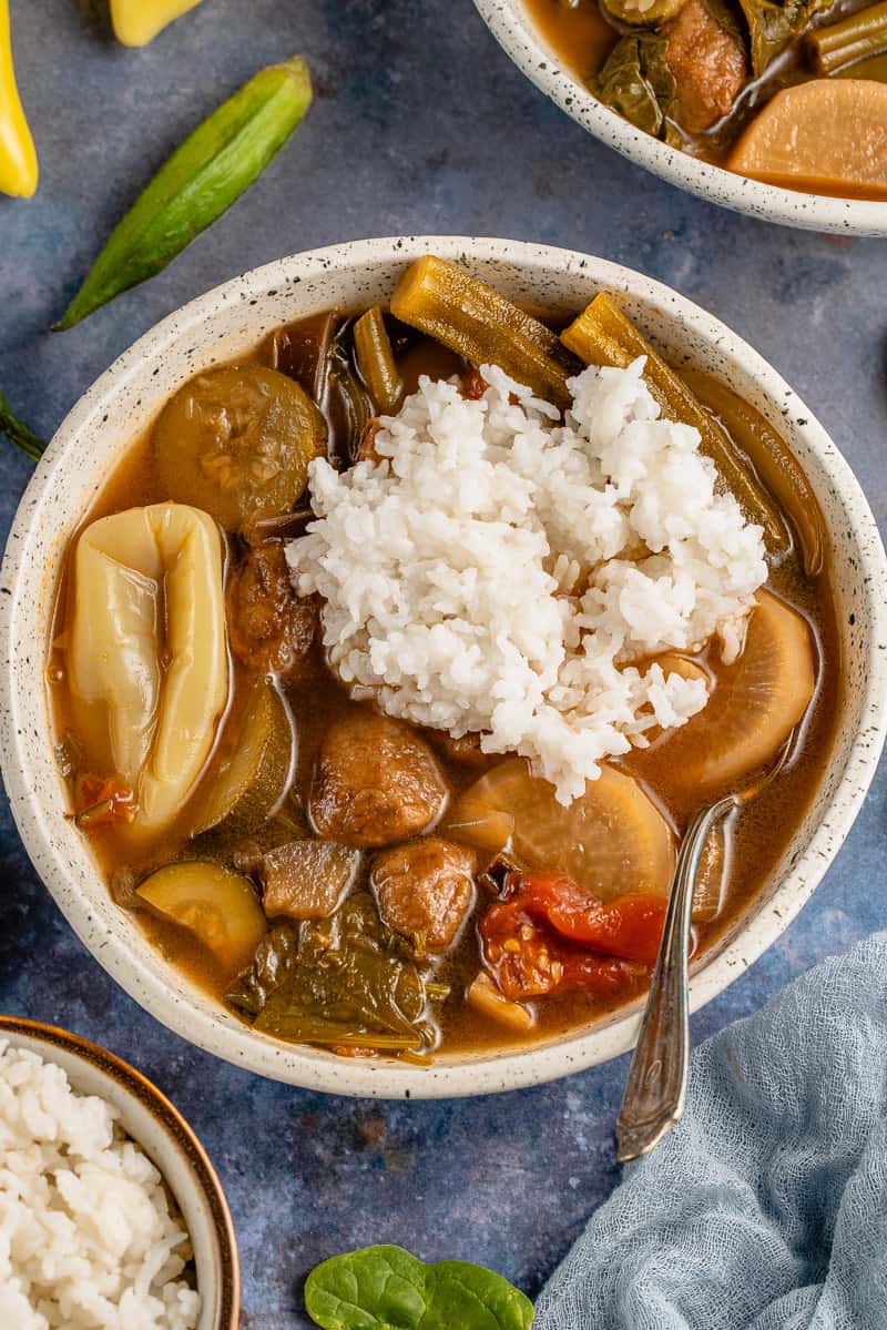 vertical photo of vegan sinigang and rice in a white bowl with a spoon