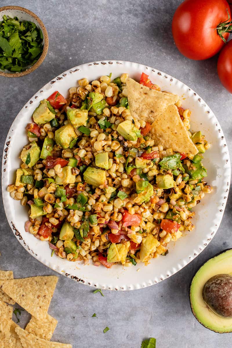 vertical photo of Avocado and Roasted Corn Salad in white bowl
