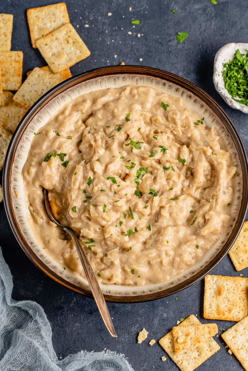 overhead image of caramelized onion dip in bowl with spoon on styled background.
