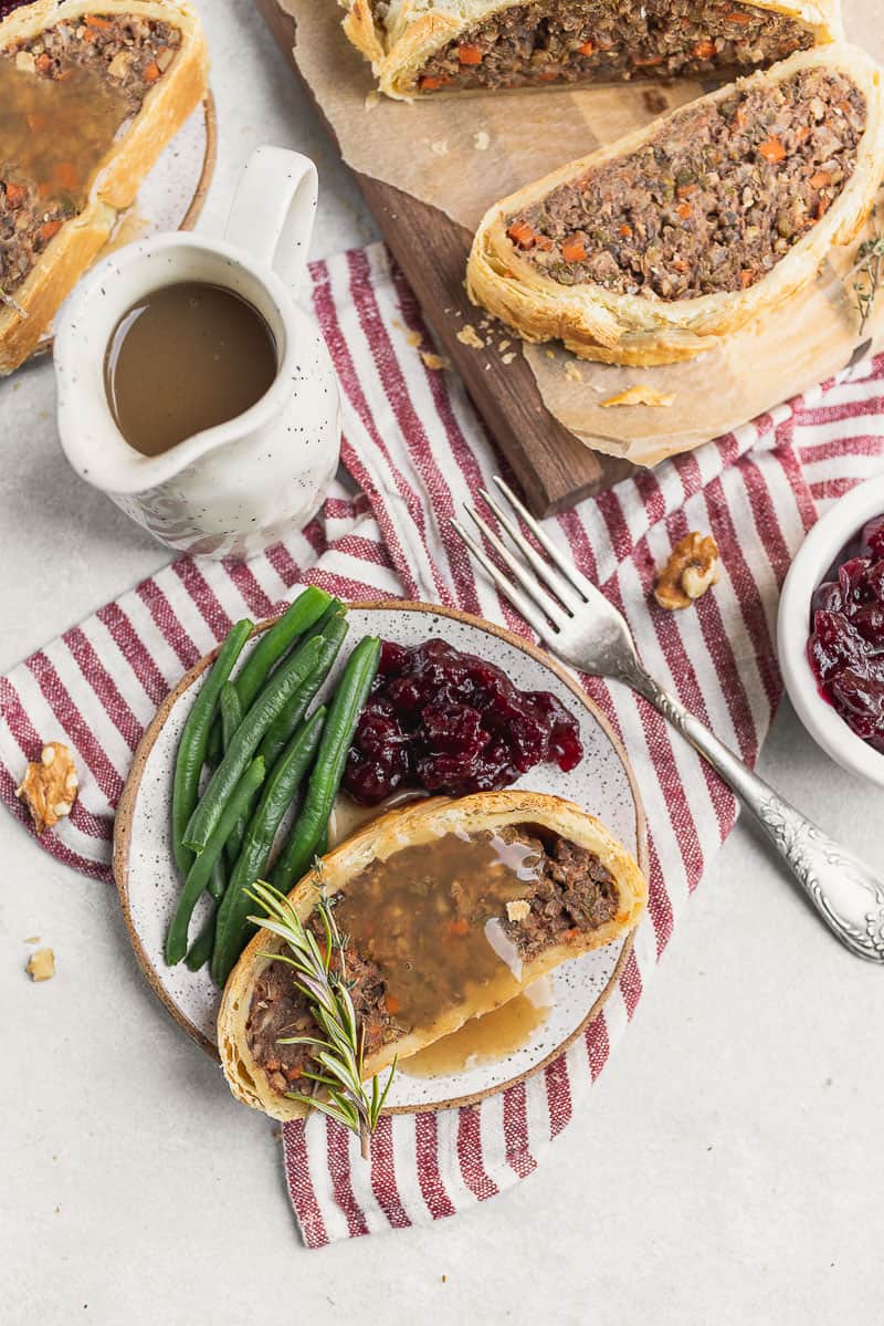 vegan wellington on a plate with gravy, cranberries and green beans