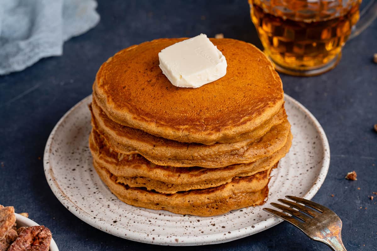 horizontal photo of a stack of vegan gingerbread pancakes on white plate