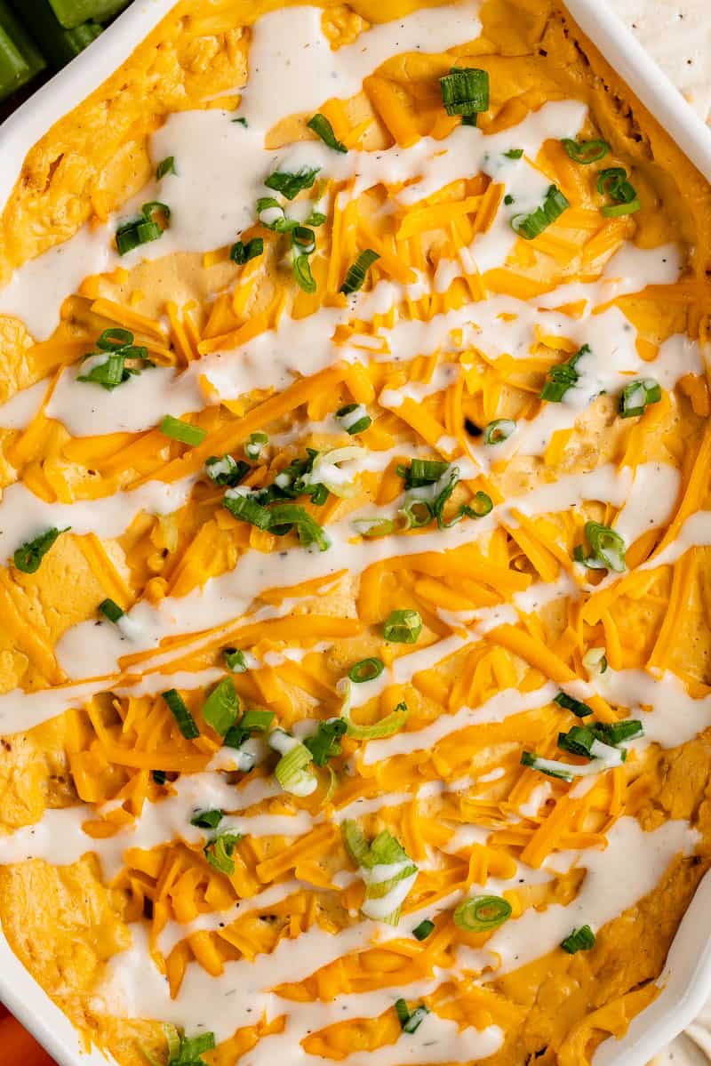 close up photo of vegan buffalo chicken dip with green onions and vegan ranch