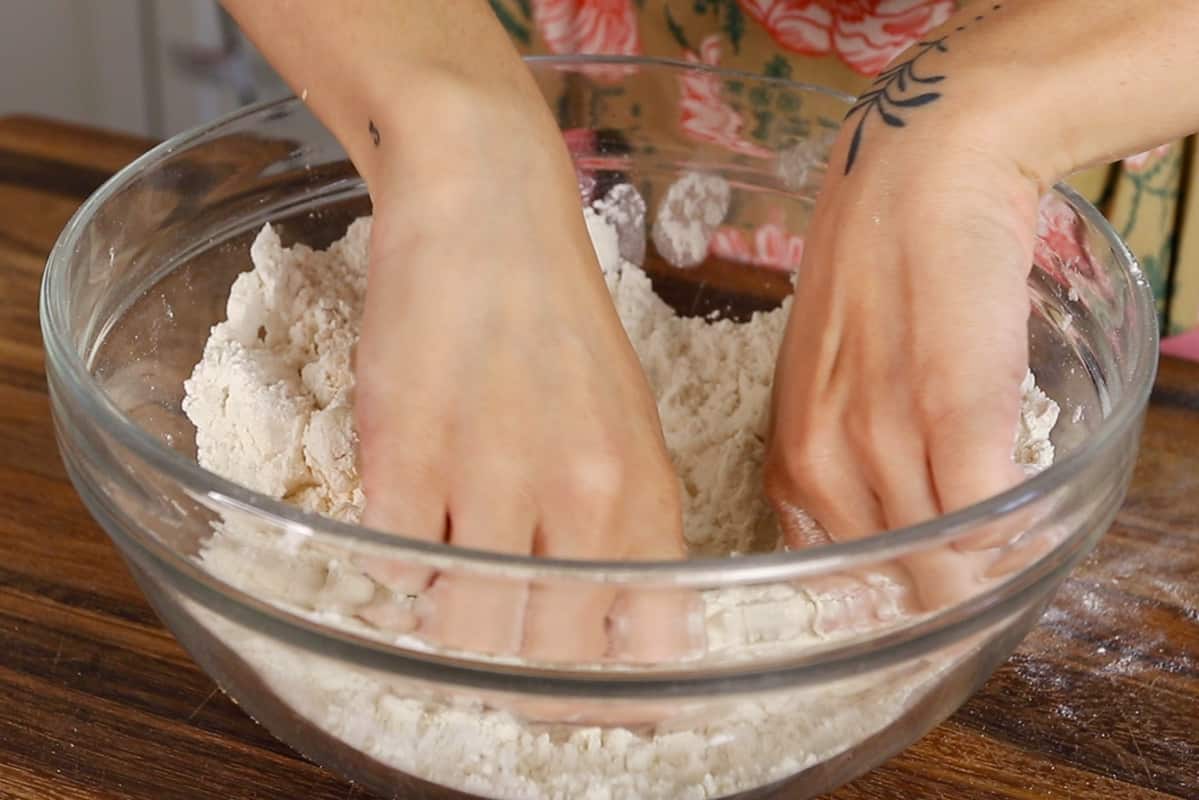 mixing vegan pie crust by hand in glass bowl
