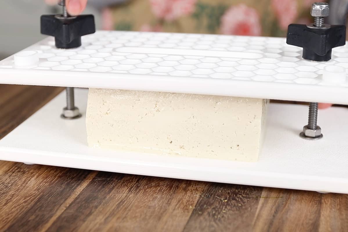 pressing tofu on wooden board