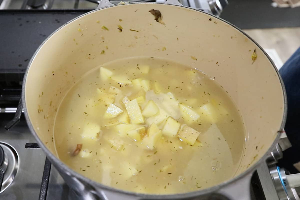 adding potatoes to large pot for vegan clam chowder