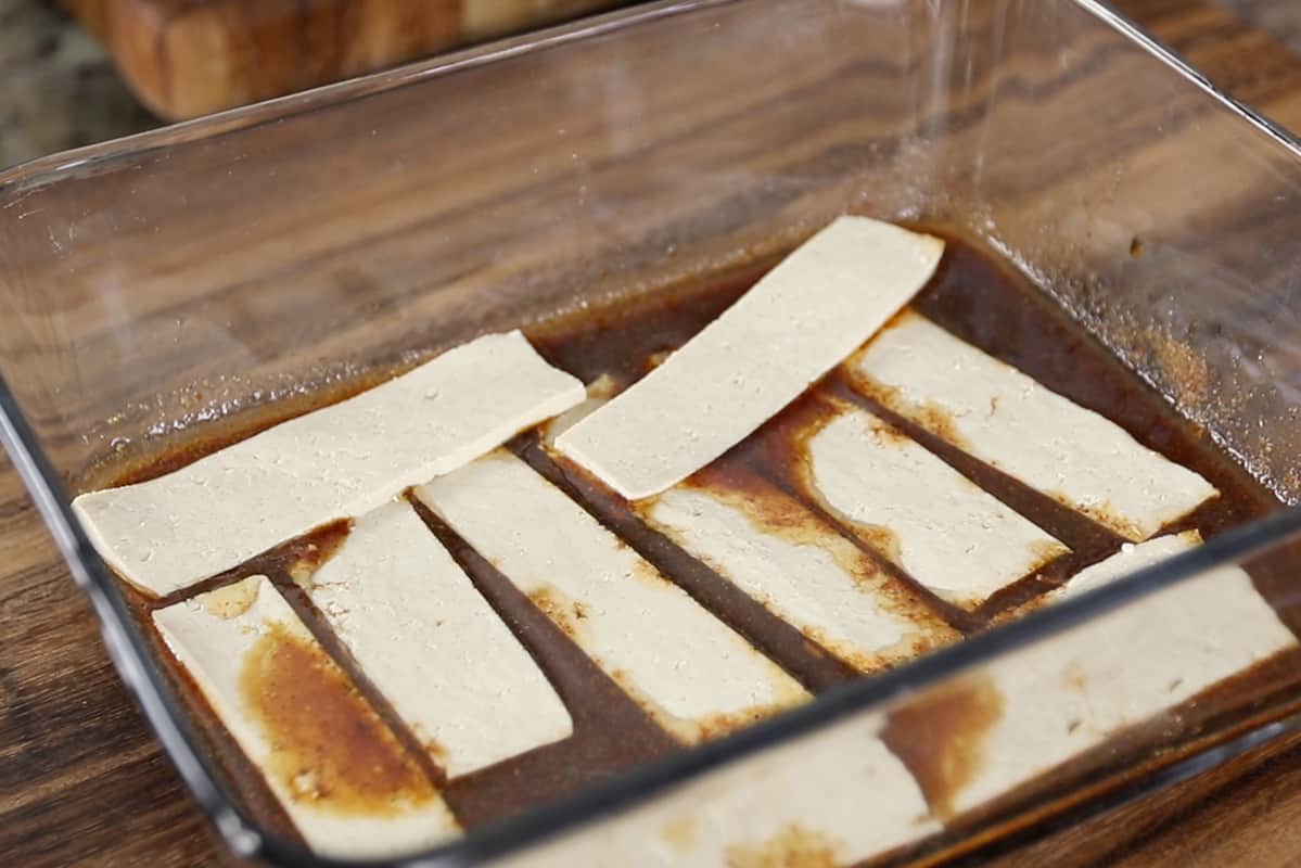marinating pieces of tofu in glass dish