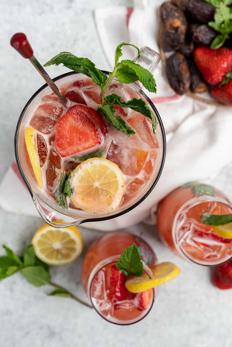 overhead photo of large full pitcher of strawberry lemonade and two full cups