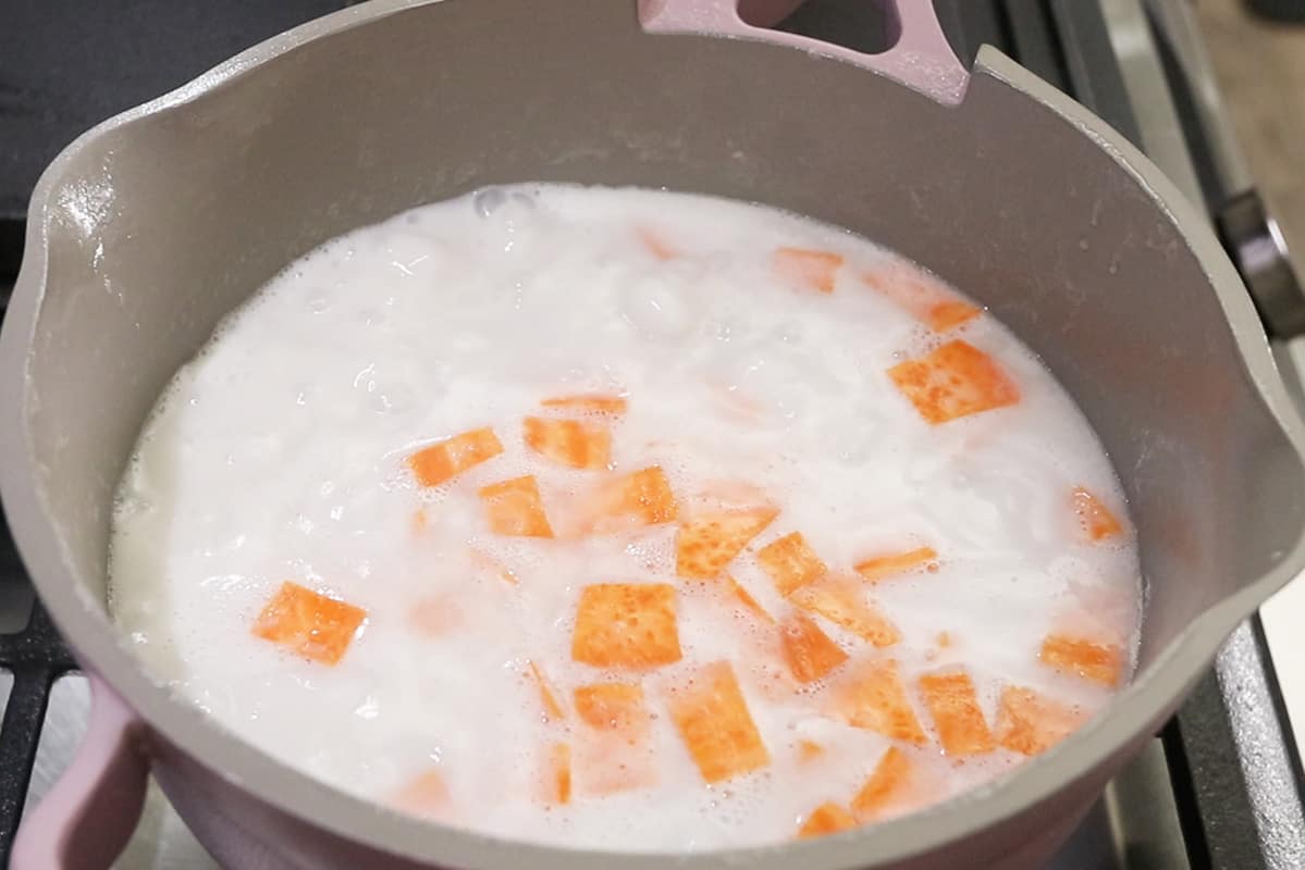 boiling orange sweet potatoes in sweet coconut soup for ginataang bilo bilo