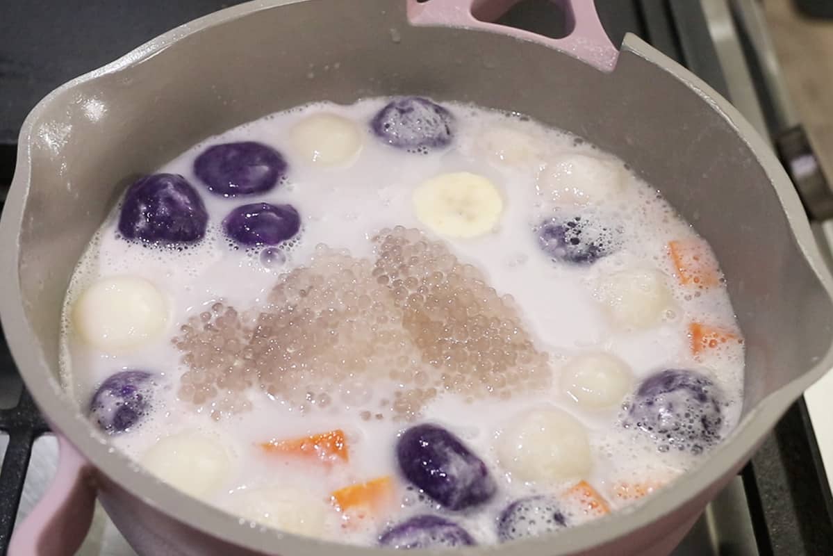 addiing cooked tapioca pearls to ginataang bilo bilo in a pot