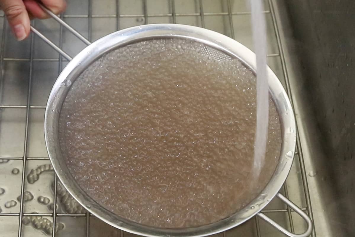 rinsing cooked tapioca pearls in a mesh strainer