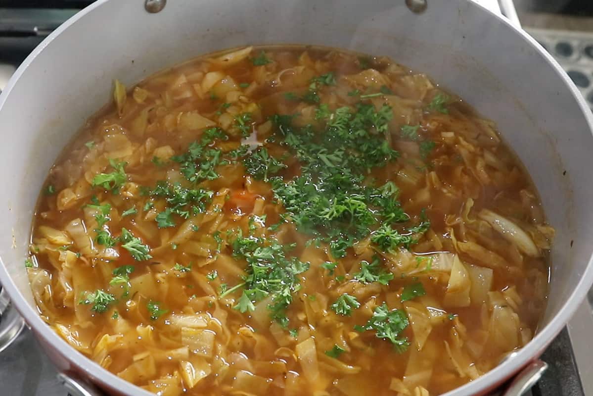 adding fresh parsley to cabbage soup in large pot