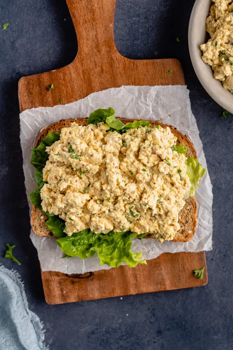 photo of vegan tofu egg salad on toast with lettuce on wooden board