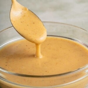 spoon with vegan honey mustard dressing in glass bowl