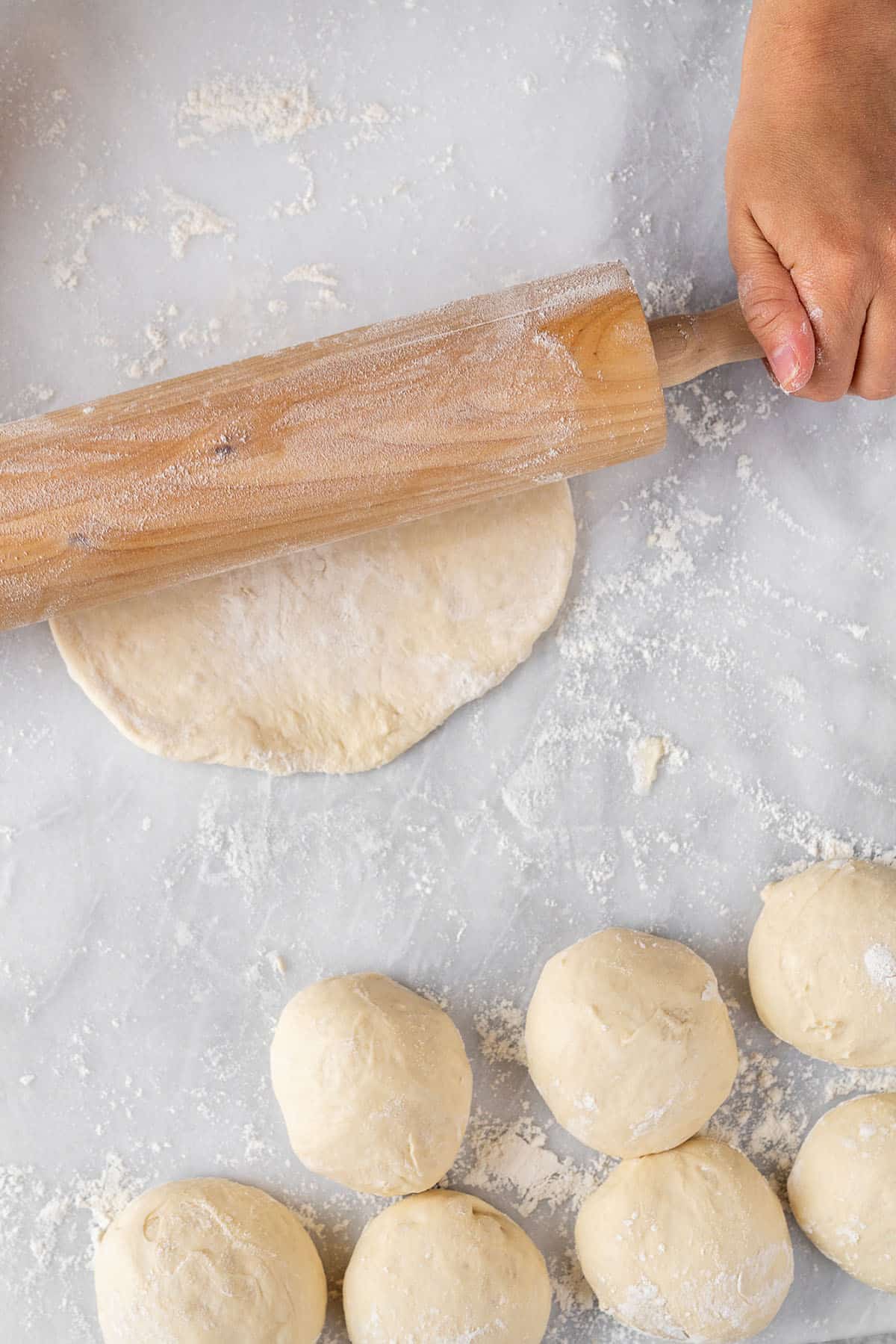 rolling out pita bread dough on marble board