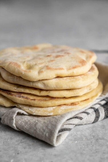 a stack of homemade pita bread on a gray cloth