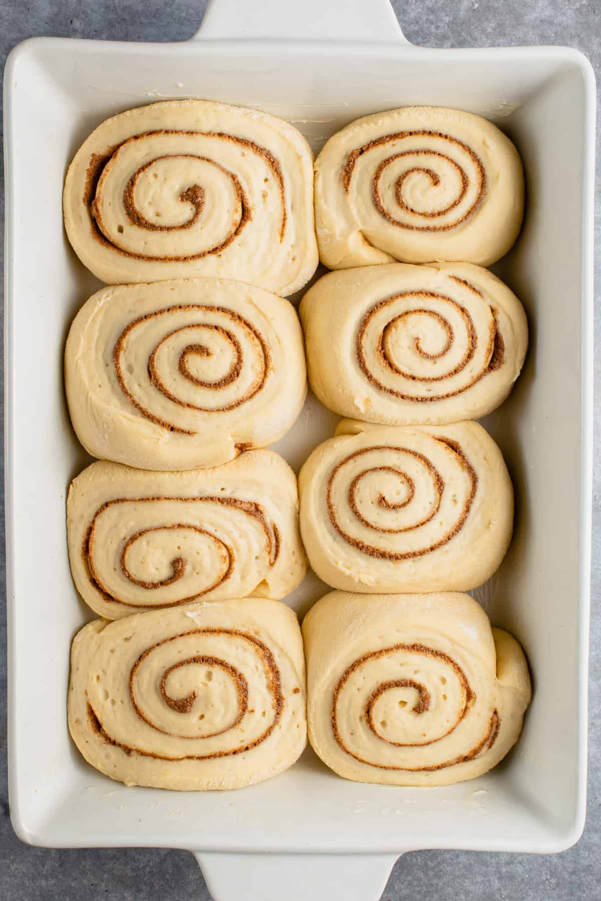 risen unbaked cinnamon rolls in baking dish