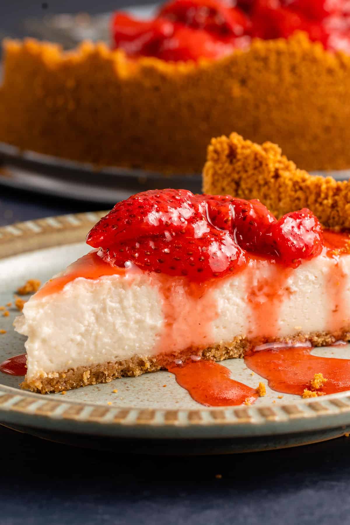 close up of vegan cheesecake with strawberry sauce on light blue plate
