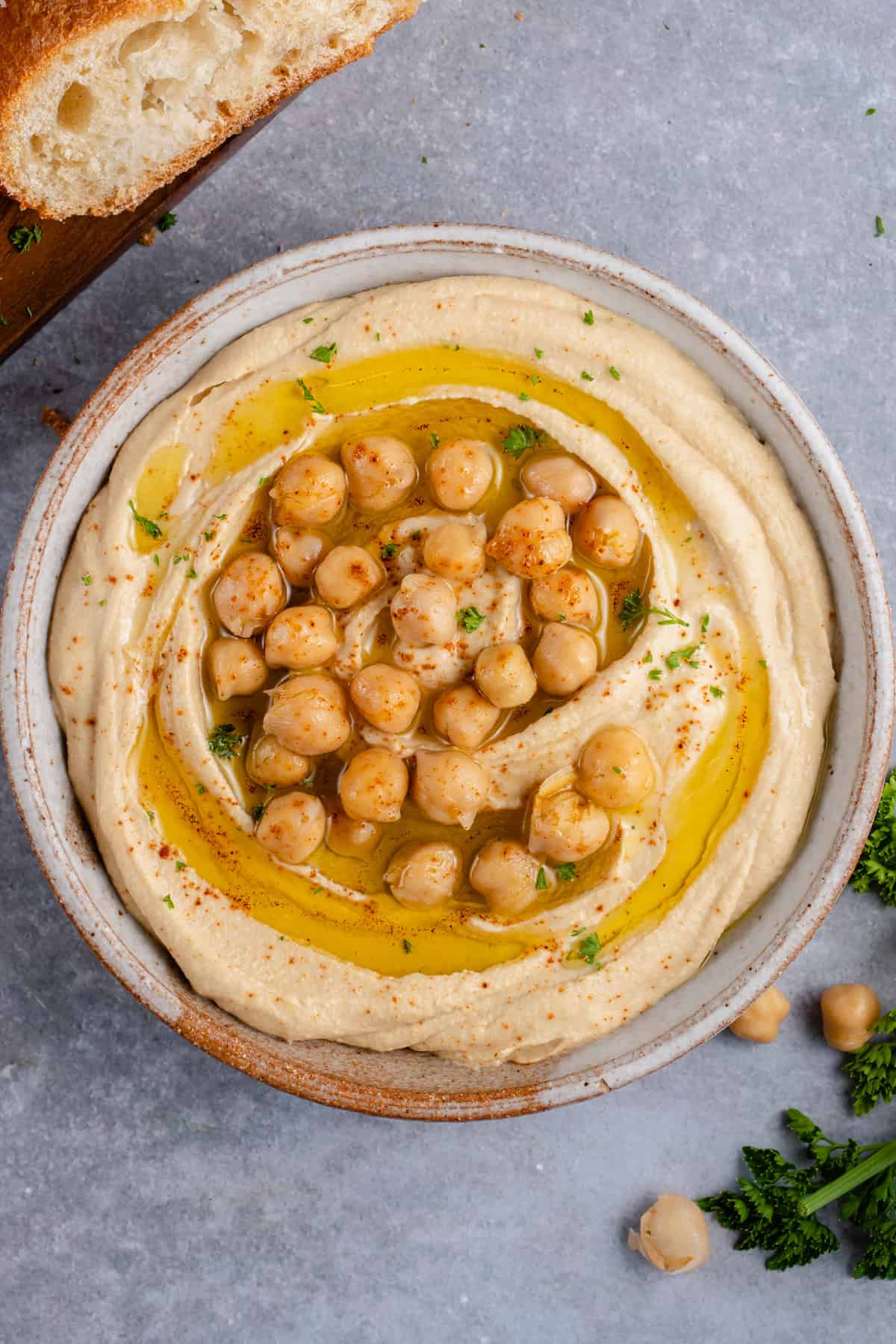close up photo of creamy hummus topped with chickpeas, olive oil and parsley
