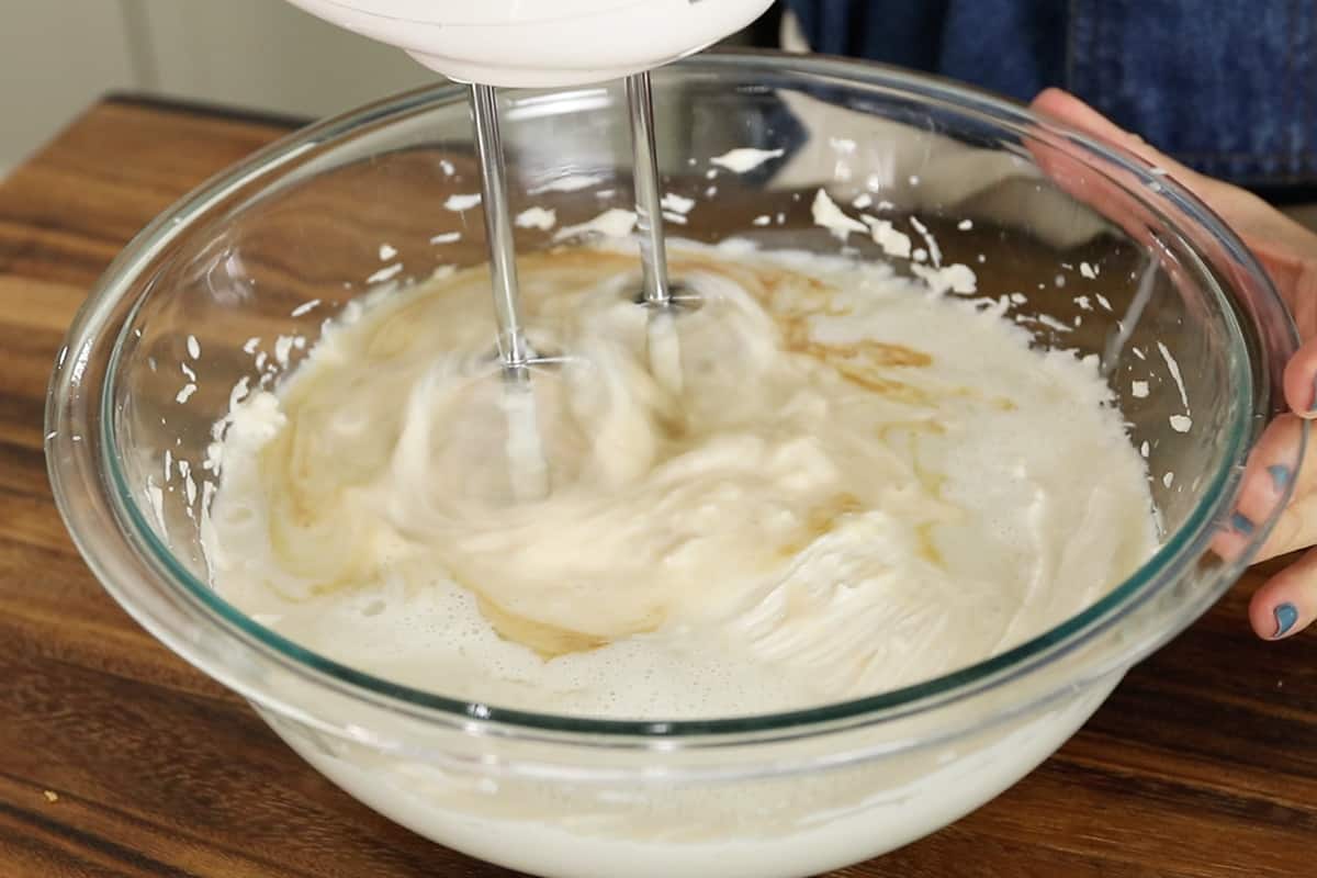 preparing nut-free vegan cheesecake filling in a glass bowl with hand mixer