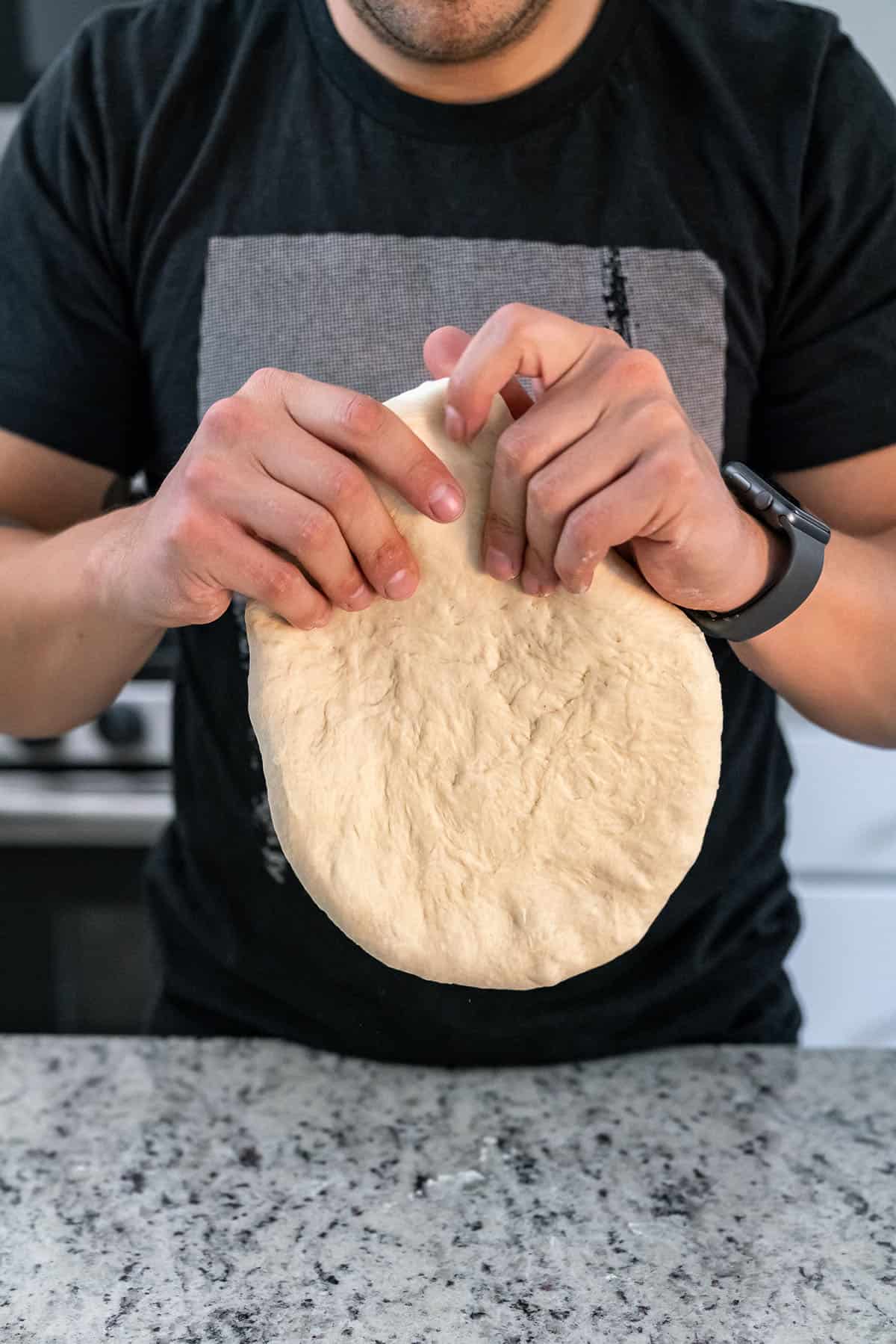 using hands to thin out pizza dough