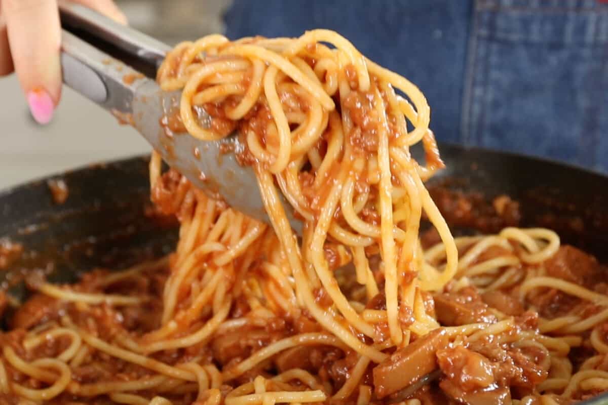 scooping filipino spaghetti with tongs