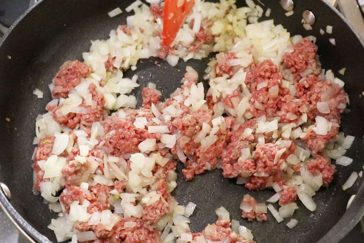 uncooked vegan ground beef and onions in black pan