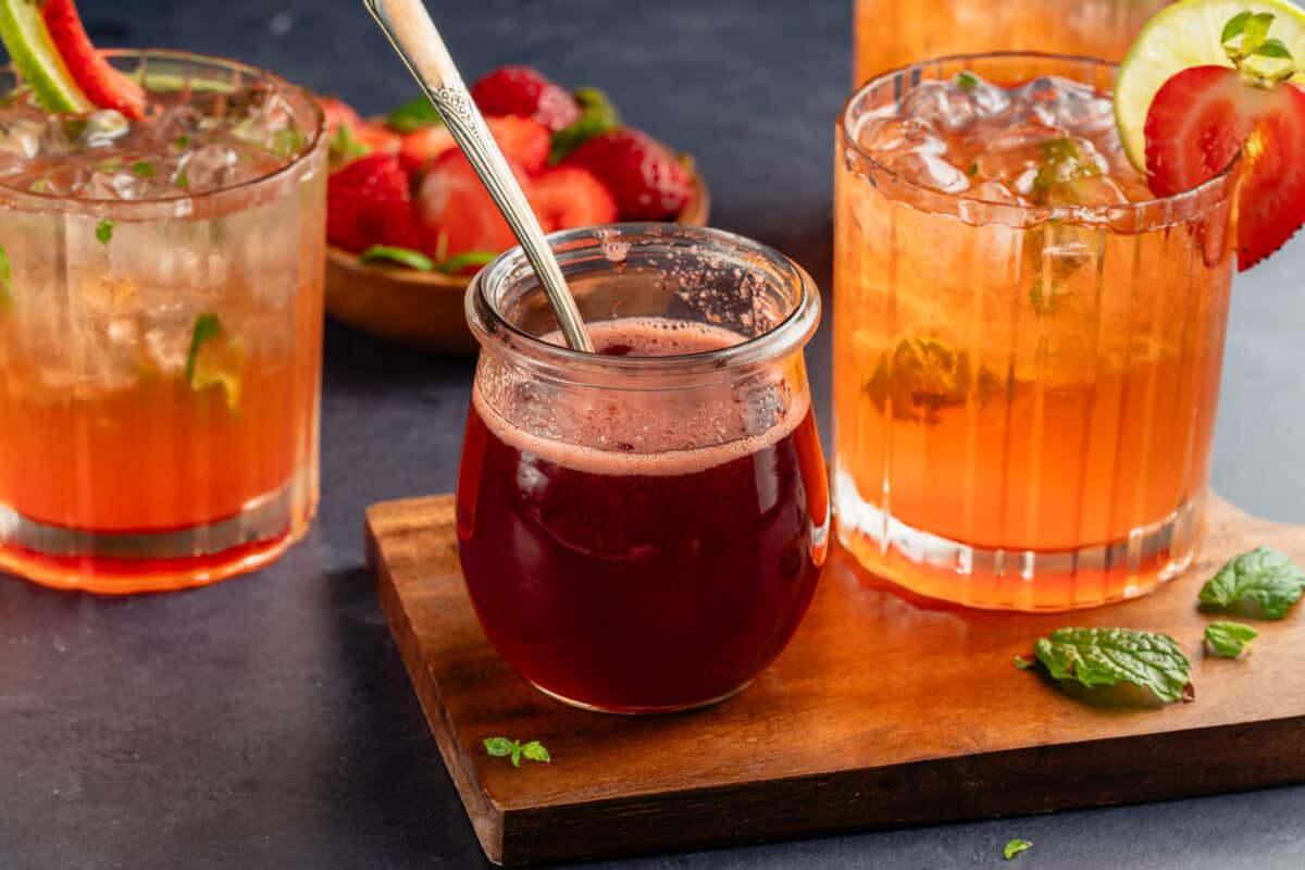 Strawberry Mojito Mocktail and strawberry syrup on a wooden board and blue table