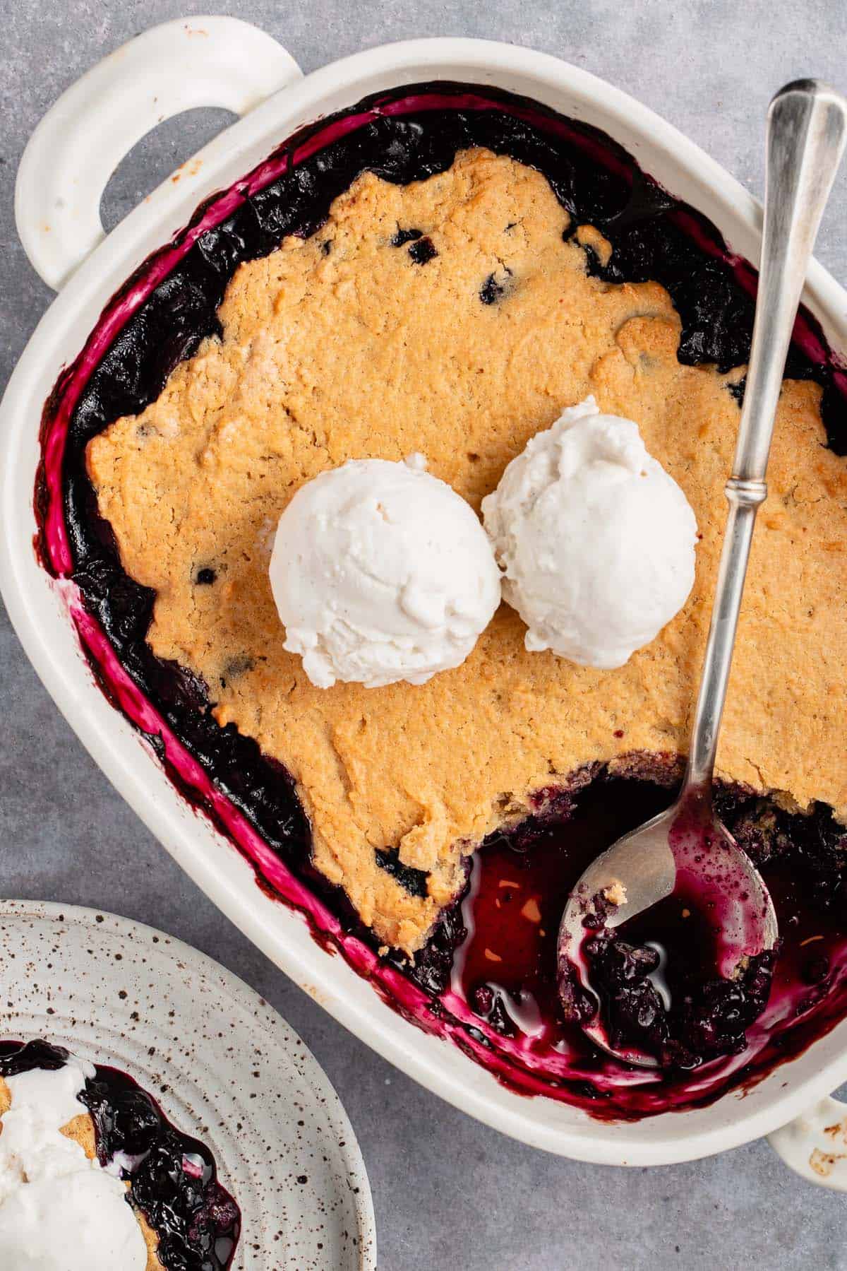 blueberry cobbler in white baking dish with ice cream