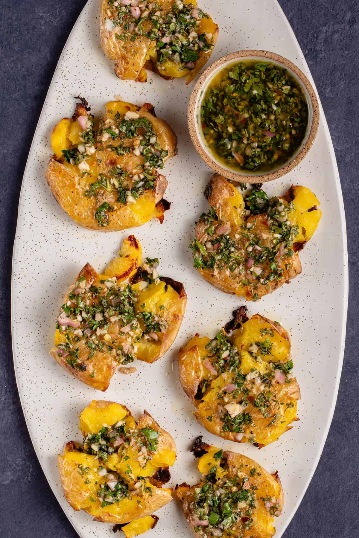 Roasted Smashed Potatoes with Chimichurri on white oval serving platter