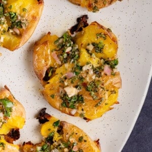 close up Roasted Smashed Potatoes with Chimichurri on white oval serving platter
