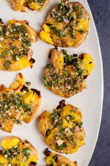 Roasted Smashed Potatoes with Chimichurri on white oval serving platter