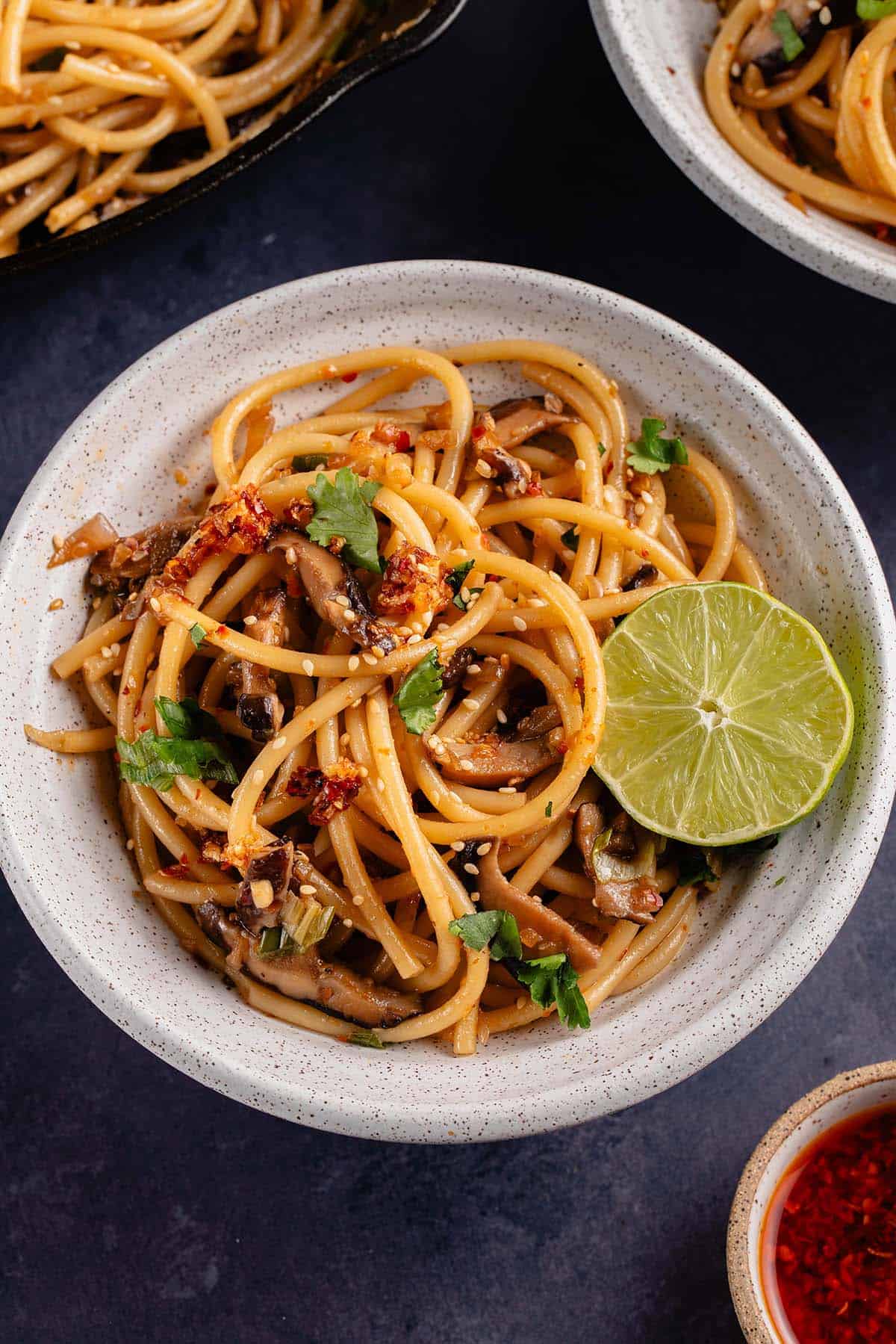 overhead photo of Spicy Chili Crisp Garlic Noodles and lime in white bowl