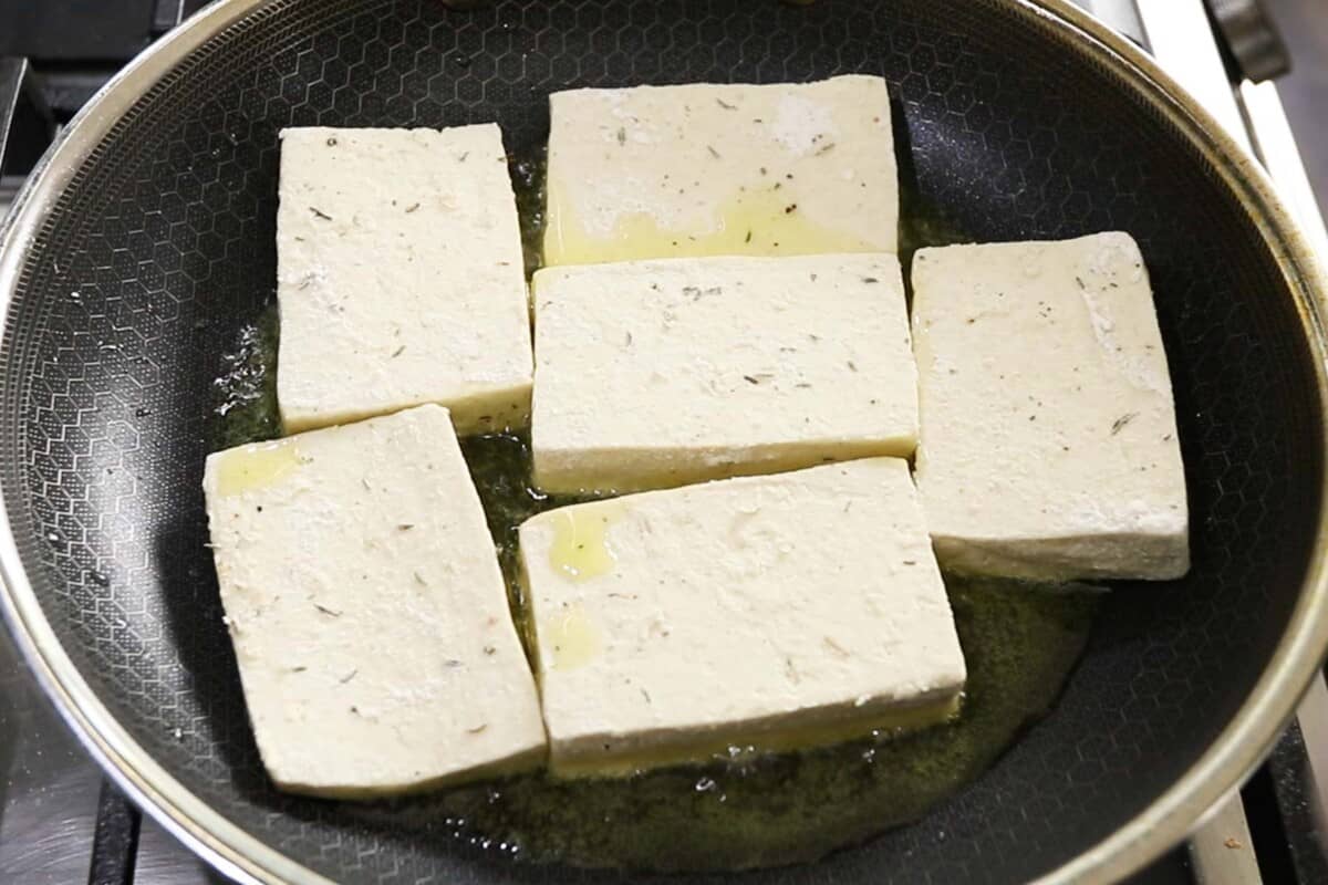 breaded tofu frying in cast iron skillet