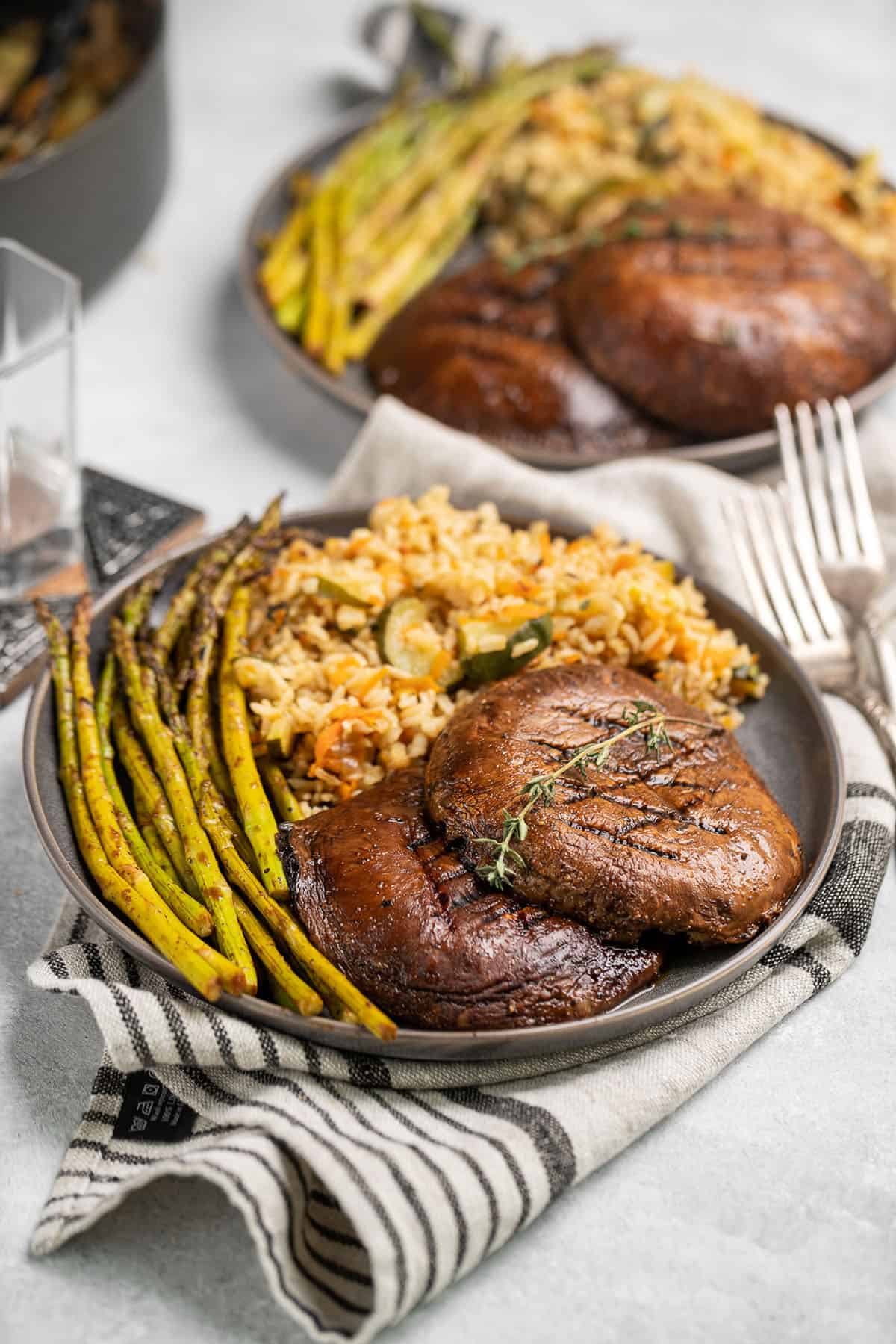 mushroom steak on gray plate with rice pilaf and asparagus