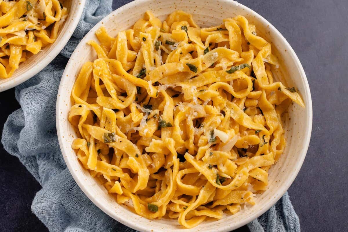 horizontal photo of Homemade Pumpkin Pasta with Sage Butter Sauce in white bowls