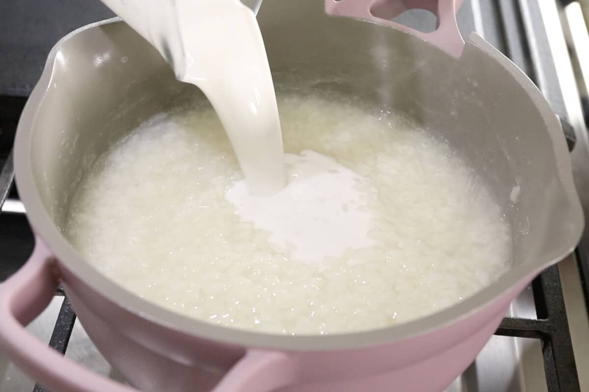 pouring coconut milk into rice for champorado