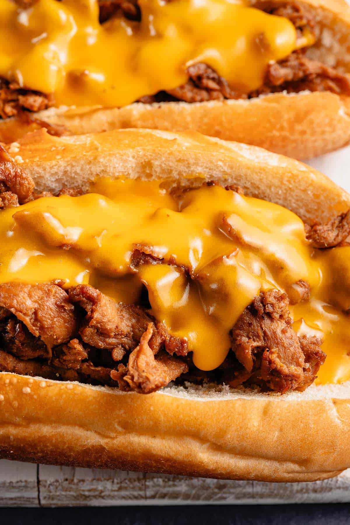 close up of 2 vegan soy curl Philly cheesesteaks on white board