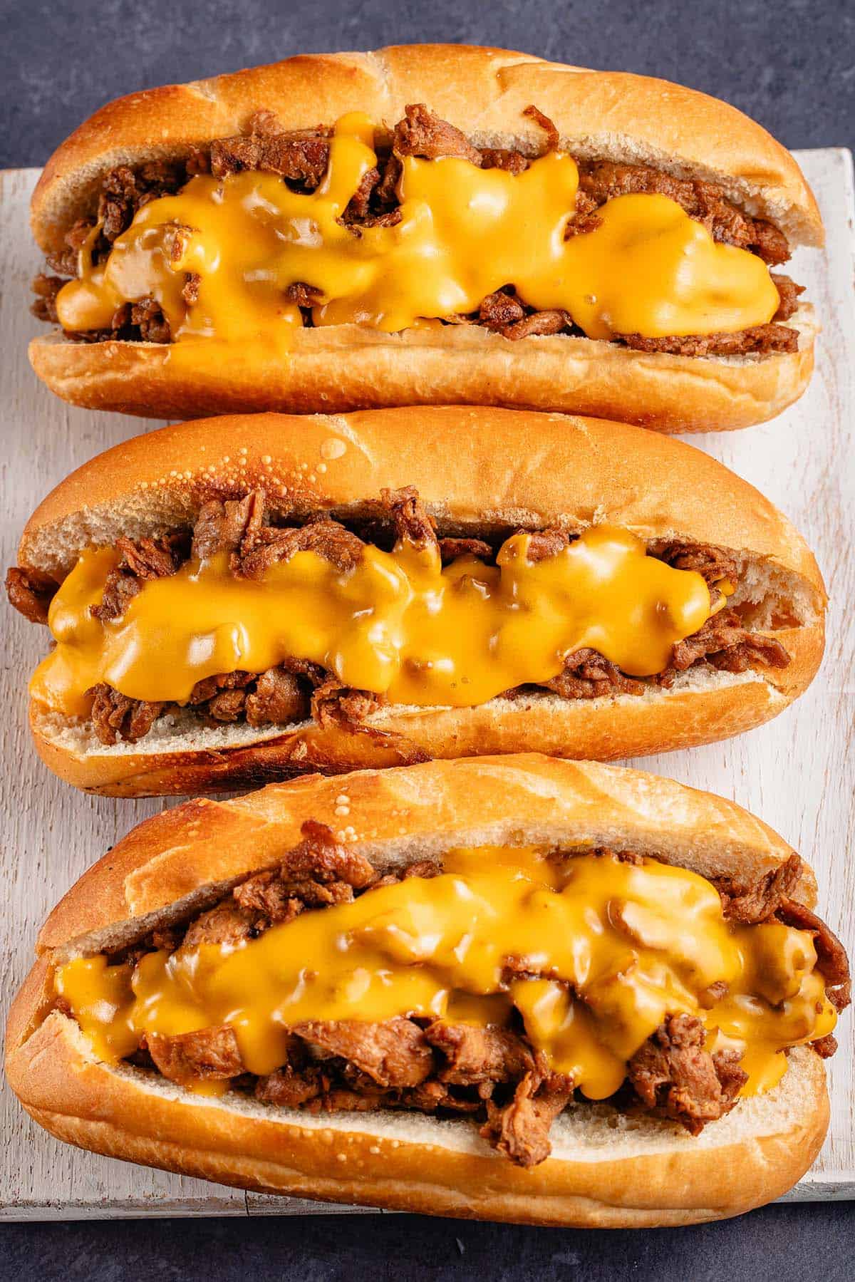 3 vegan soy curl Philly cheesesteaks on white board