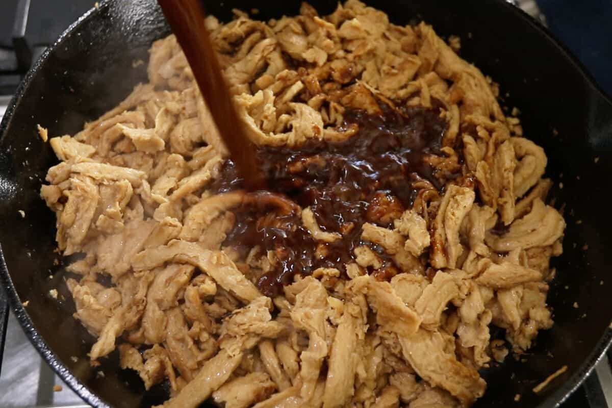 cooking soy curls for vegan cheesesteak in cast iron skillet