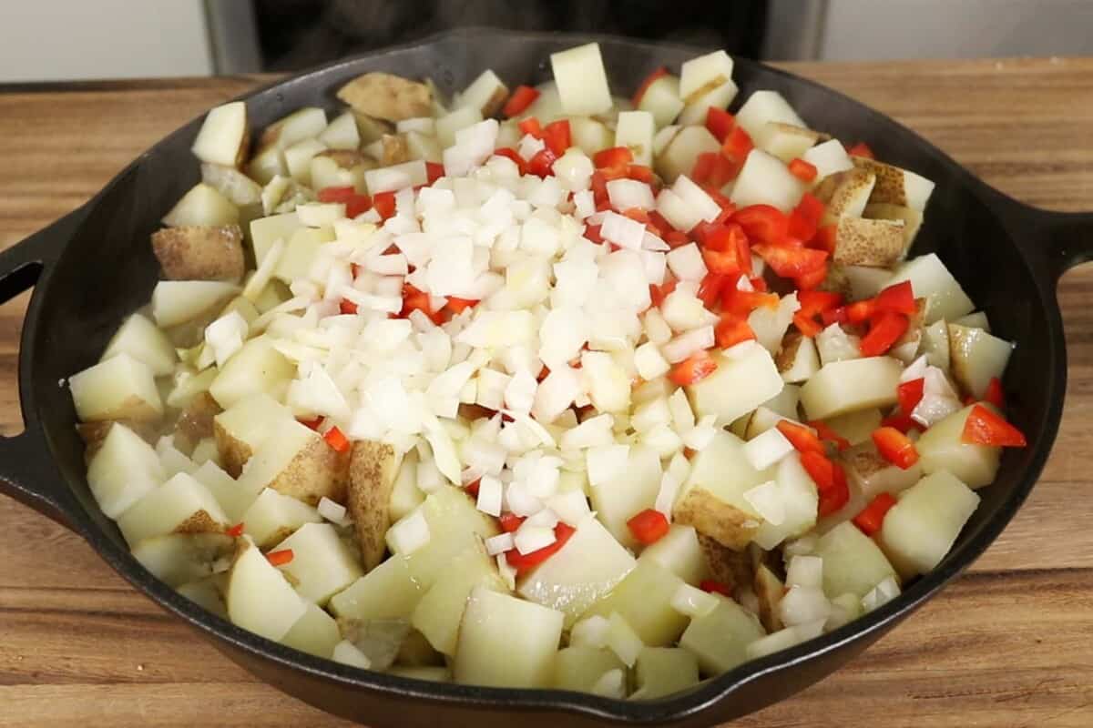 onions and peppers on potatoes in skillet