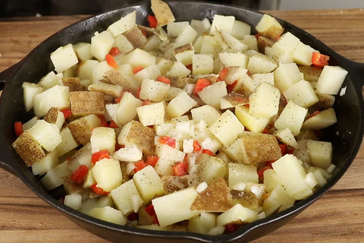 seasoned potatoes peppers and onions in a skillet