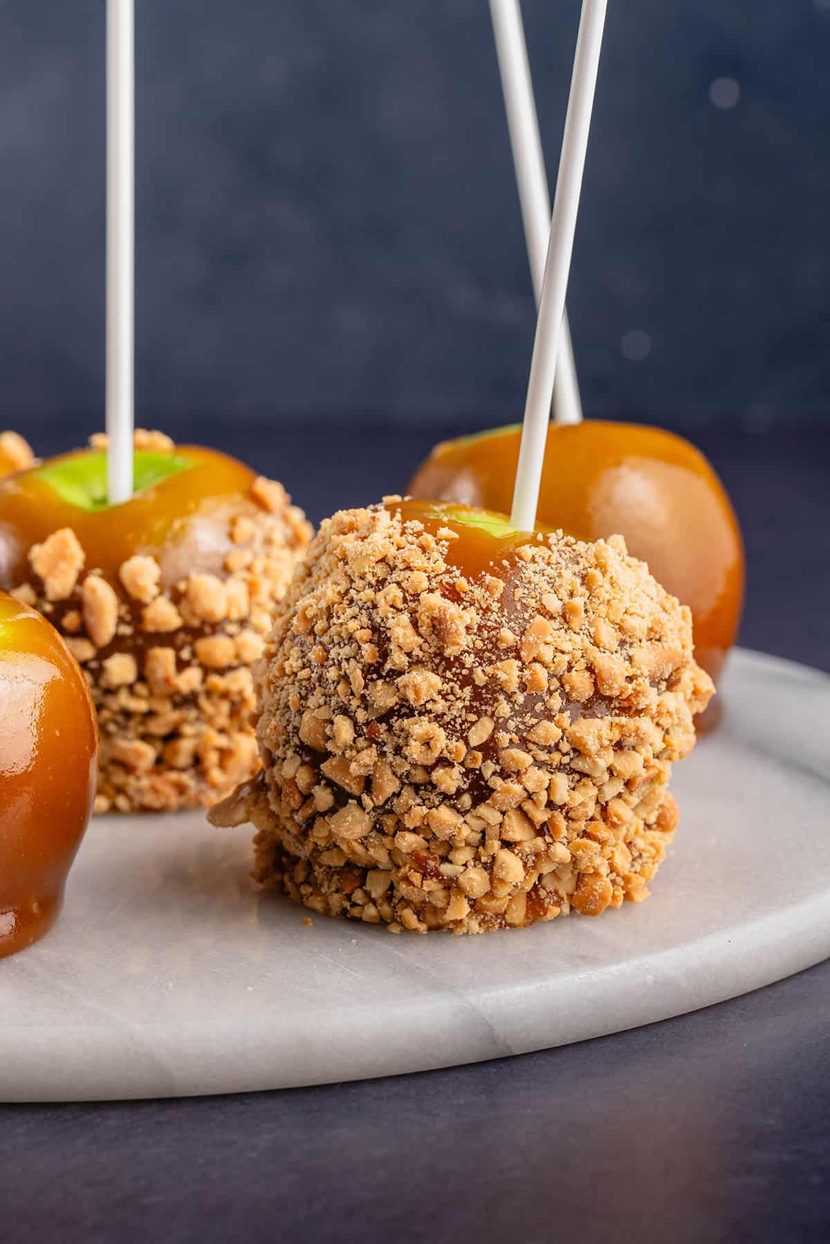 close up photo of vegan caramel apple with peanuts on white board