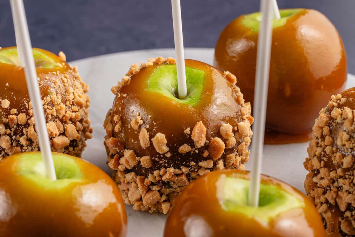 6 caramel apples with peanuts on round marble board
