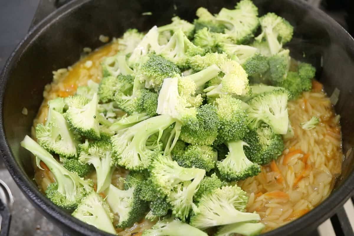 making vegan broccoli cheddar orzo in black pot