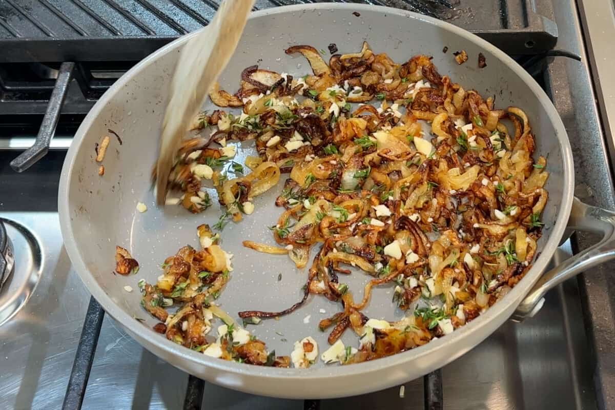 making caramelized onions with garlic and thyme in grey pan for french onion mashed potatoes