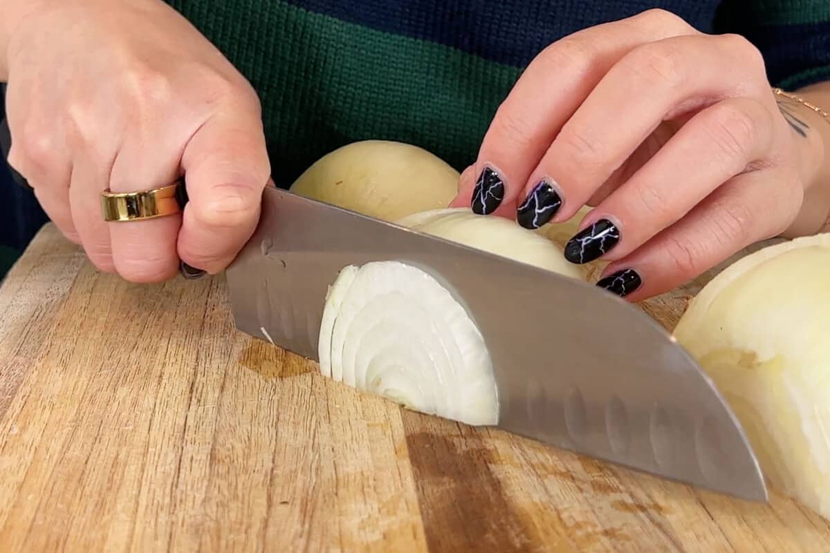 thinly slicing onions on wooden board
