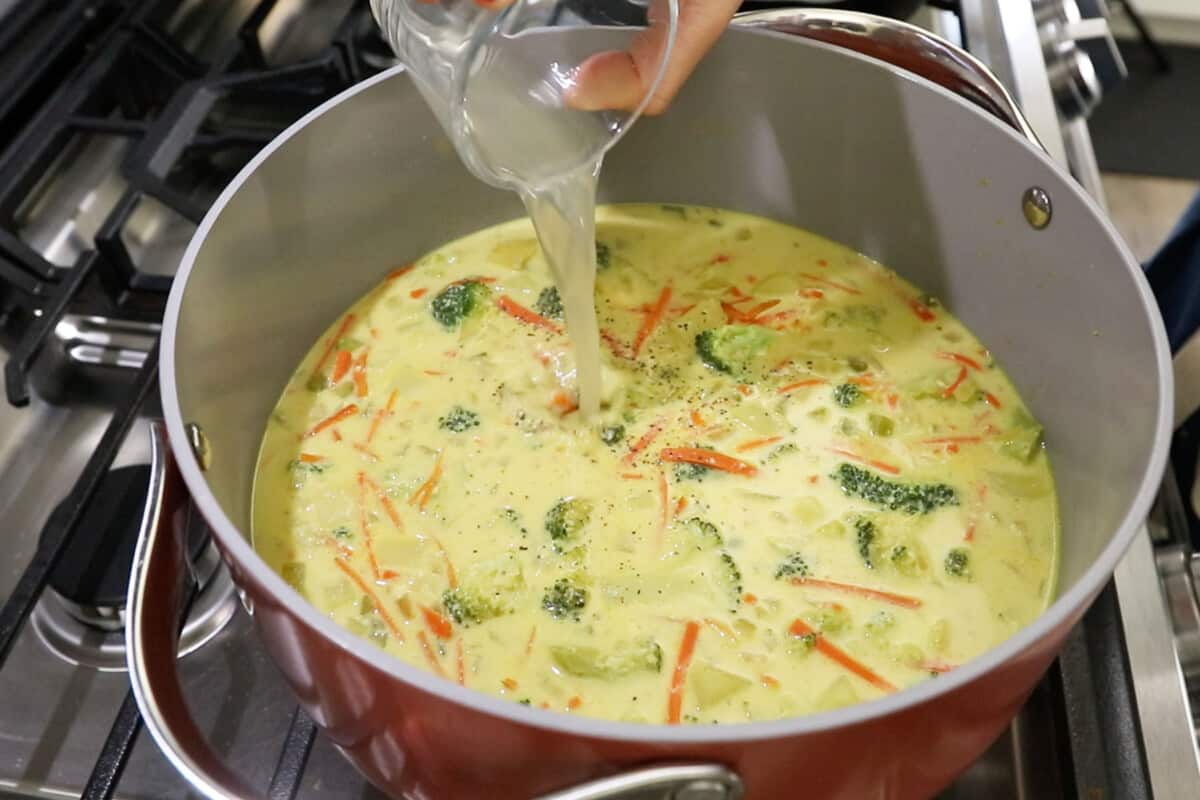 making vegan broccoli potato soup in large pink pot