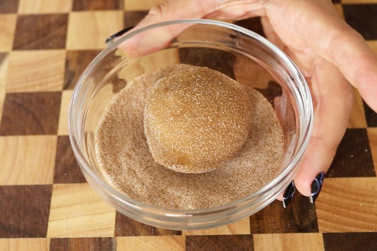 rolling vegan pumpkin sugar cookies in granulated sugar