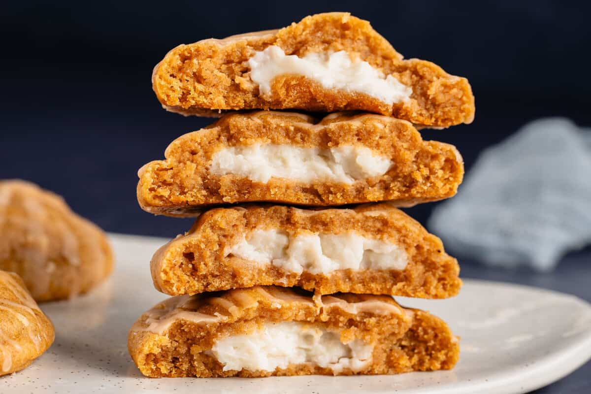 stacked pumpkin cheesecake cookies with cream filling showing